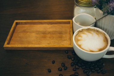 Kafede ahşap masada kahve bardağı ve kahve çekirdekleri