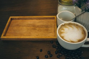 Kafede ahşap masada kahve bardağı ve kahve çekirdekleri