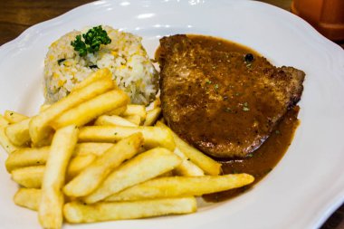 ahşap masada beyaz plaka ile biftek 