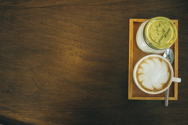 Taza de café y granos de café en la mesa de madera en la cafetería —  Fotos de Stock
