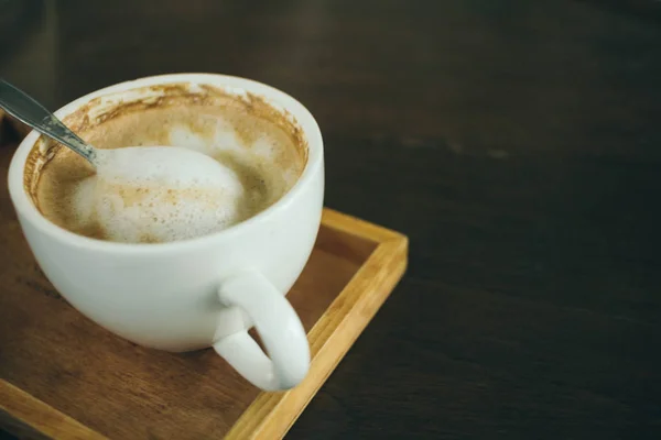 Φλιτζάνι καφέ και κόκκους καφέ σε ξύλινο τραπέζι στο καφέ — Φωτογραφία Αρχείου