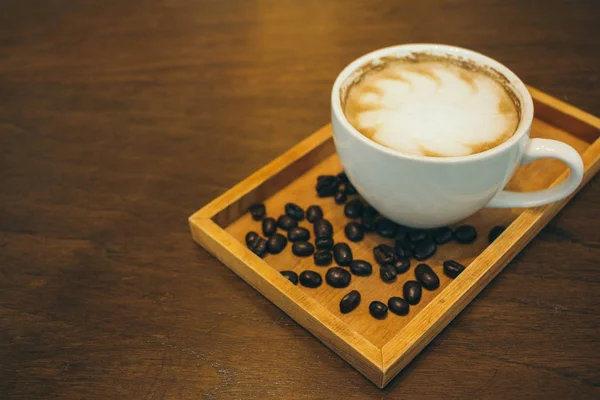 Kafede ahşap masada kahve bardağı ve kahve çekirdekleri