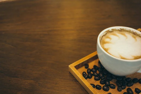 Kávéscsésze és kávé bab fa asztal kávézóban — Stock Fotó