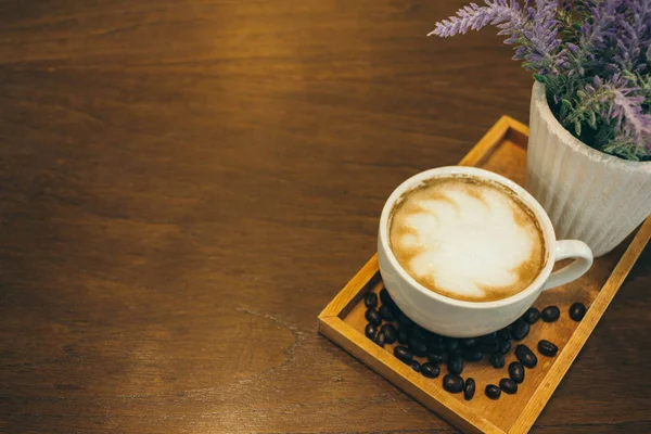 Φλιτζάνι καφέ και κόκκους καφέ σε ξύλινο τραπέζι στο καφέ — Φωτογραφία Αρχείου