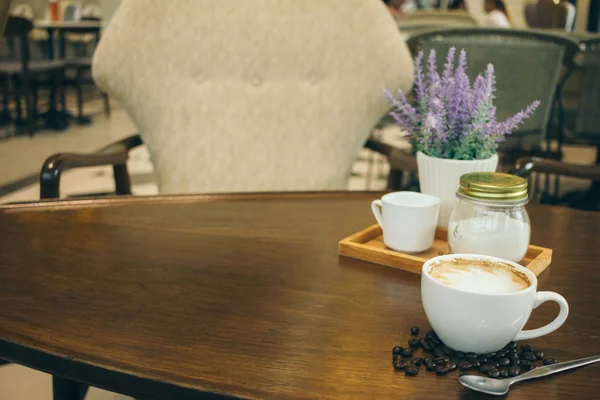 Taza de café y granos de café en la mesa de madera en la cafetería — Foto de Stock