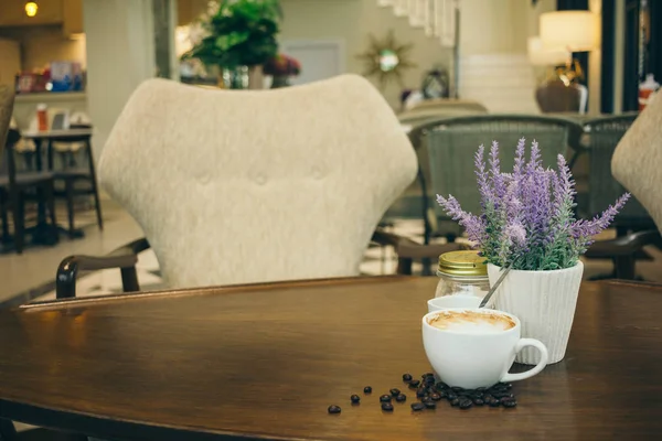 Taza de café y granos de café en la mesa de madera en la cafetería — Foto de Stock