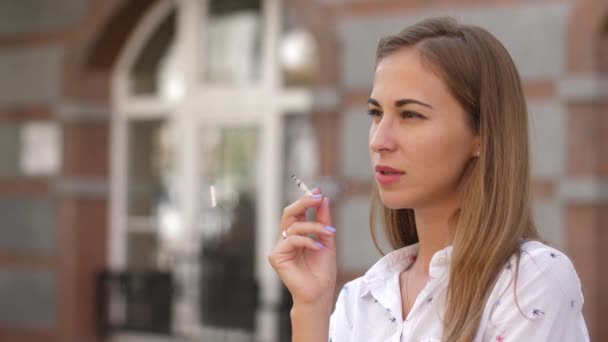 Jeune belle femme fume dans la rue. 4k. au ralenti — Video