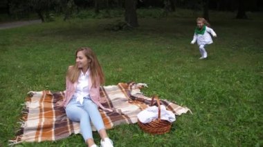 Küçük kız annesiyle sonbahar parkta oynarken. 4 k. ağır çekim.