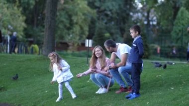 Genç, mutlu bir aile. Baba, Oğul, anne ve kızı ekmek ile parkta kuşlara. 4 k. ağır çekim