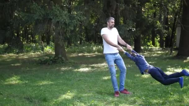 El joven padre gira en el parque de otoño con su hijo. Feliz juego y risa. A cámara lenta. 4K . — Vídeos de Stock