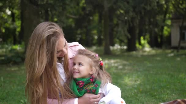 Jovem mãe feliz com sua filha sorrindo para a câmera no parque de outono. 4K. Movimento lento — Vídeo de Stock