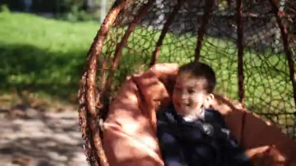 Feliz lindo niño caucásico, alegre, alegre niño divertido bebé está montando en swing en vacaciones soleadas. 4k. Moción lenta — Vídeo de stock