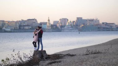 Mutlu erkek ve kız sarılmak ve uzaktan izlemek. Birbirimize el ele tutuşup gülümse. Sonbahar beach 4k yavaş Mo