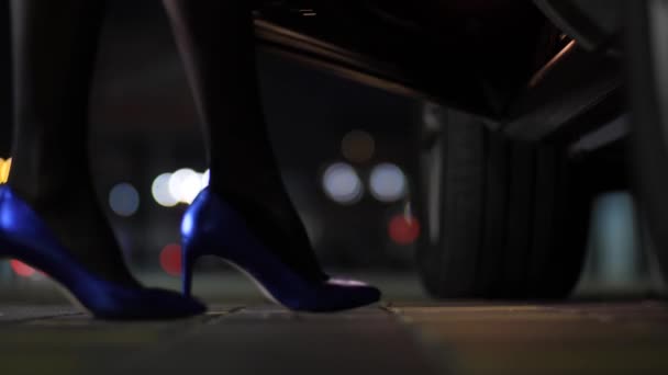 Γκρο πλαν όμορφη λεπτή γυναικεία πόδια σε μπλε υψηλής φτέρνα παπούτσια να πάρει στο αυτοκίνητο τη νύχτα πέρα από το υπόβαθρο bokeh citylights 4k Slow Mo — Αρχείο Βίντεο