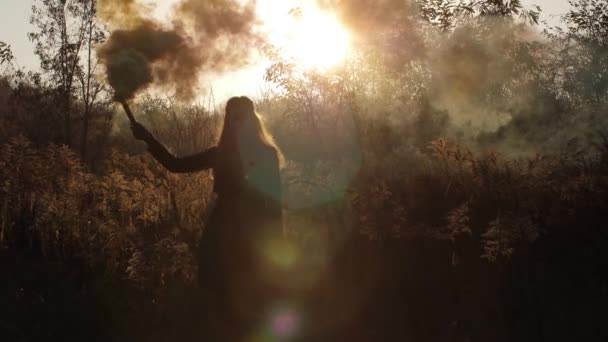 Модна дівчина ходить у полі, несучи спалахи диму, що вивільняють хмари жовтого диму 4K Slow Mo — стокове відео
