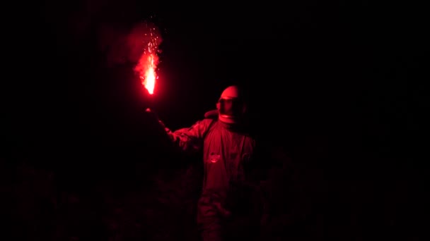 I de mörka astronaut spins, med sitt röda ljus i sin hand. Astronauten går genom det höga gräset 4k Slow Mo — Stockvideo