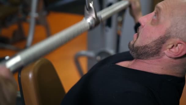 Close up van bodybuilder gezicht. Man schudt handen en spieren weer op de simulator 4k Slow-Mo — Stockvideo