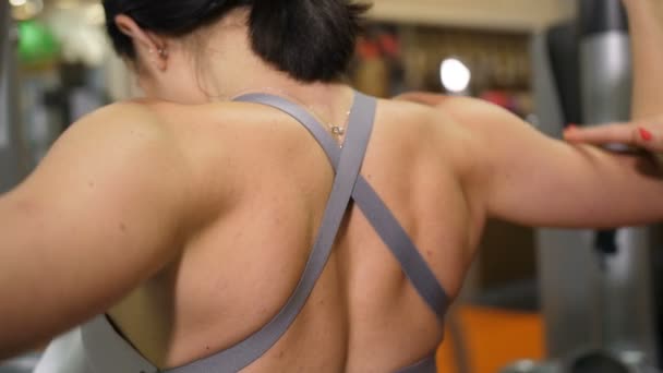 Fechar as lâminas. Menina esbelta treme os músculos dos braços e costas no ginásio 4K Slow Mo — Vídeo de Stock