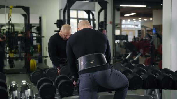 Bodybuilder takes heavy dumbbells, looks at himself in the mirror, does the exercise 4K Slow Mo — Stock Video