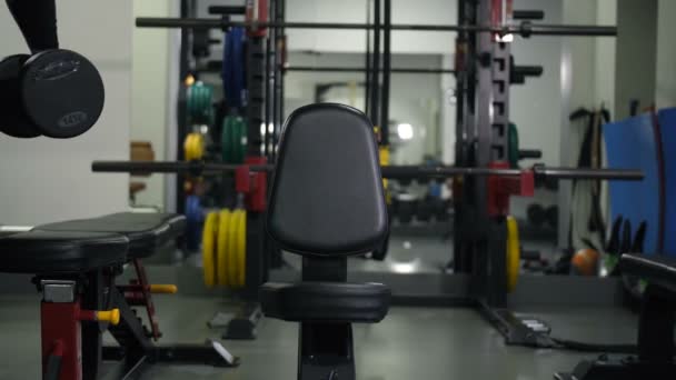 El atleta con pesas se sienta en un banco, hace un ejercicio para dos manos 4K Slow Mo — Vídeos de Stock