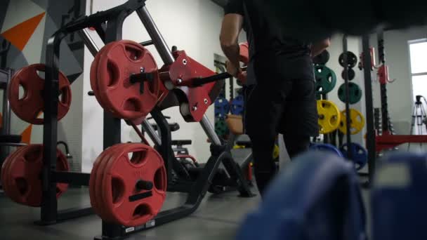 Gimnasio. Un hombre viene al simulador. Comienza a levantar el peso con sus pies 4K Slow Mo — Vídeos de Stock