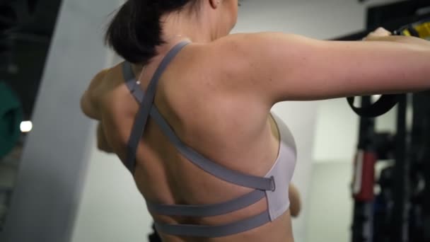 Primer plano. La espalda de una chica deportiva. Mujer hace tirando de TRX 4K Lento Mo — Vídeo de stock