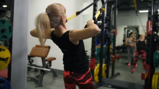 Adult athletic woman doing exercises on the TRX in the sports club 4K Slow Mo — Stock Video