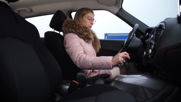 Светловолосая девушка поворачивает руль машины, меняет передачу, выключает машину, выходит из машины 4K Slow Mo — стоковое видео