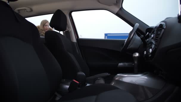 Блондинка садится в машину, включает зажигание, переключает передачу, катается на 4K Slow Mo — стоковое видео