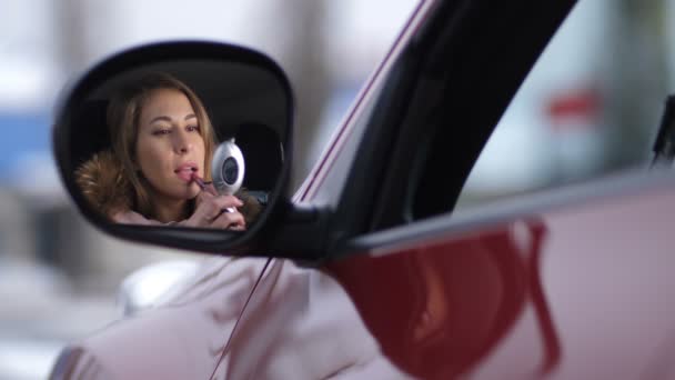 Hermosa chica en el coche pinta los labios con lápiz labial rosa,. Reflexión en el espejo lateral 4K Slow Mo — Vídeo de stock