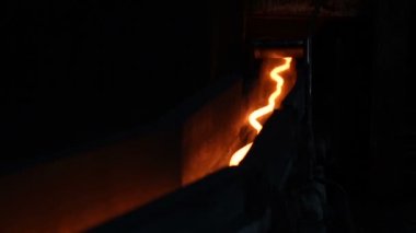 Tünele doğru sürünen bir yılan gibi sıcak çelik ince bir iplik. Metal üretim.