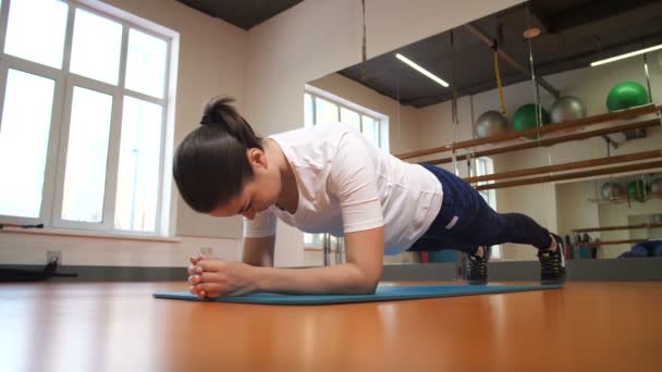 A rapariga treina no clube de fitness. Faz uma prancha de exercício. 4K Mo lento — Vídeo de Stock