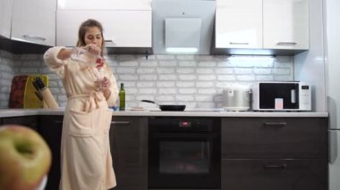 Evde, kız mutfakta, su içiyor ve gülümsüyor. 4 k yavaş Mo