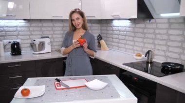Bir kadın modern mutfakta biber kadar alır, kalbe koyar ve sebze açar. Gülümseme pas için yol verir. Kırık bir kalp sembolü. 4 k yavaş Mo