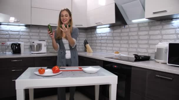 The girl in the kitchen fun juggling cucumbers. She is very happy. 4K Slow Mo — Stock Video