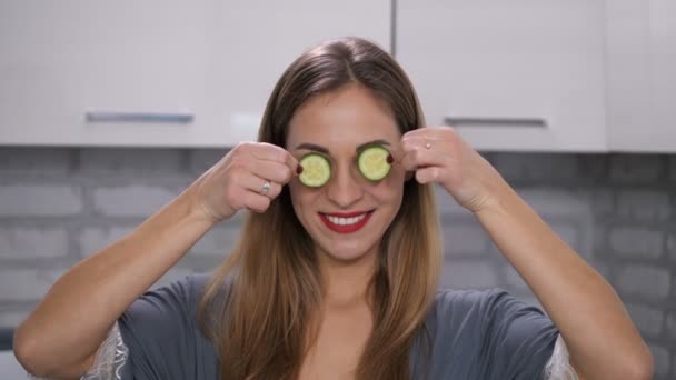 Retrato de uma linda garota que coloca pedaços de pepino nos olhos e sorri. 4K Mo lento — Vídeo de Stock