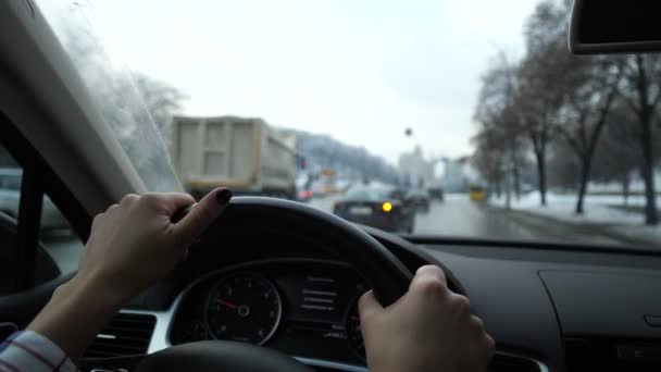 Gros plan. Les mains des femmes mènent la voiture. Devant la fenêtre se trouve une ville d'hiver. Mo lent 4K — Video