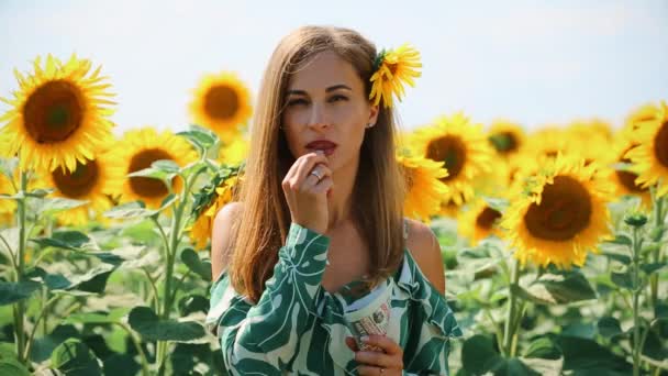 Storyboard con donna in girasoli. Campo giallo con girasoli. In primo piano c'è una ragazza vestita di verde che mangia semi . — Video Stock