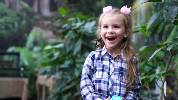 La petite fille se réjouit sincèrement, une pose de papillon sur sa tête. Mo lent 4K — Video