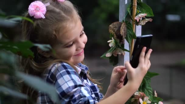 Bir kız bir selfie bir kelebek ile alır. Ekranın önünde poz bebek. 4 k yavaş Mo — Stok video