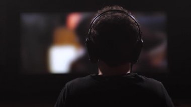 Adam bir film izlerken kulaklık. Kulaklýklý mikrofon setini kaldırır, alır ve bırakır. 4 k yavaş Mo