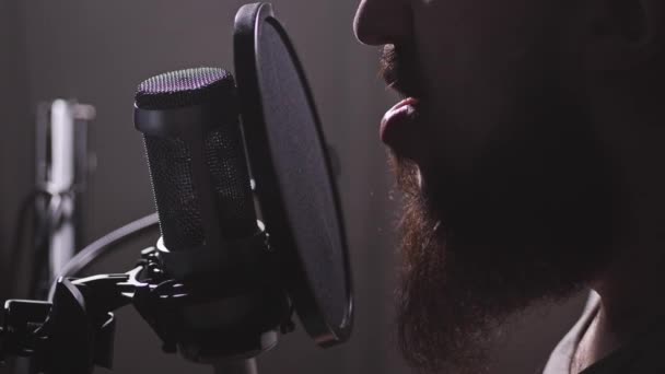Un micrófono en el estudio, aparece un hombre, comienza a recitar o tararear. 4K Slow Mo — Vídeo de stock