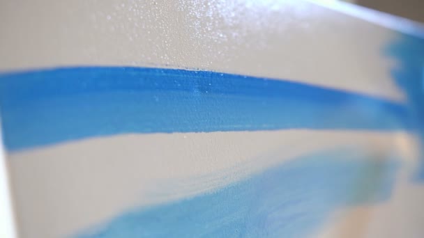 Close-up. Vrouw schildert een foto. Mooie penseel bewegingen met blauwe verf op canvas. 4k trage mo — Stockvideo