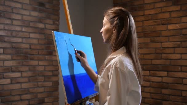 Novice artist paints the landscape. Palette knife girl makes a beautiful blue sky. 4K Slow Mo — Stock Video