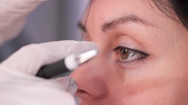 Close-up, meisjes ogen. De specialist tekent de juiste vorm van de wenkbrauwen met een draad. Beauty Clinic. 4k slow mo — Stockvideo