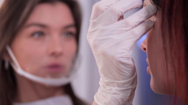 Im Schönheitsstudio richtet die Kosmetikerin die Augenbrauen in Nahaufnahme auf die Kundin aus. 4k langsam mo — Stockvideo