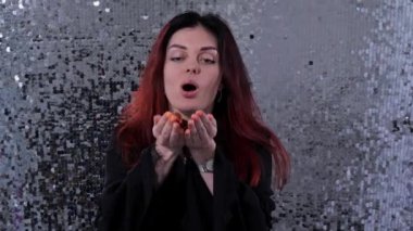 Kız neşeyle kameraya altın konfeti üfler. 4k Yavaş Mo