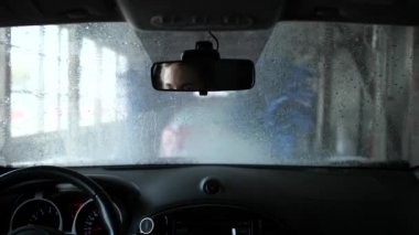Otomatik araba yıkama araba. Kulübeden ateş ediyor. Aynada bir kadın sürücünün gözleri var. 4k Yavaş Mo