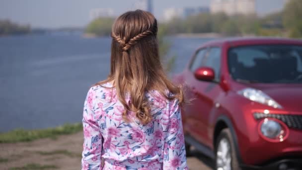 La fille se tient avec son dos, regarde la voiture, tourne brusquement, attrape les clés, sourit et les agite dans le cadre. Mo lent 4K — Video