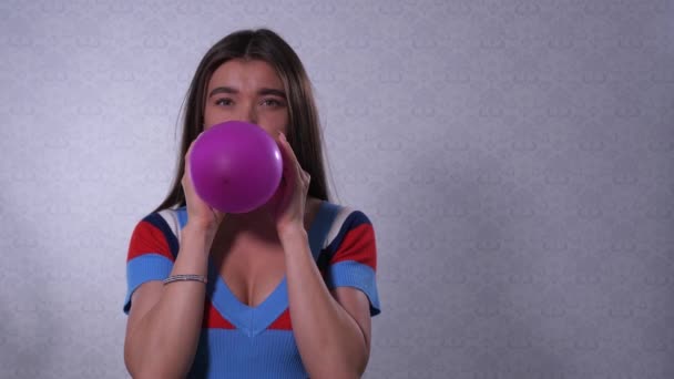 A menina infla um balão roxo, pega na mão e solta, a bola é levada e voa para longe. 4K Mo lento — Vídeo de Stock